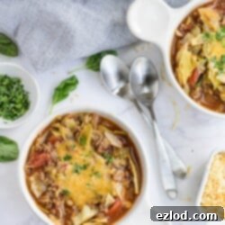 Two spoons are placed between bowls of unstuffed cabbage soup, ready to enjoy.