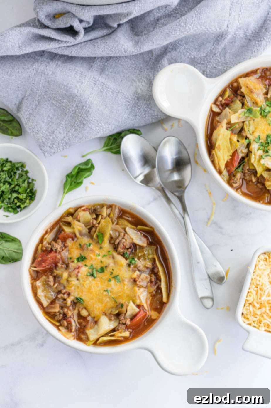 Two spoons are placed between bowls of hearty unstuffed cabbage soup, ready to be enjoyed.