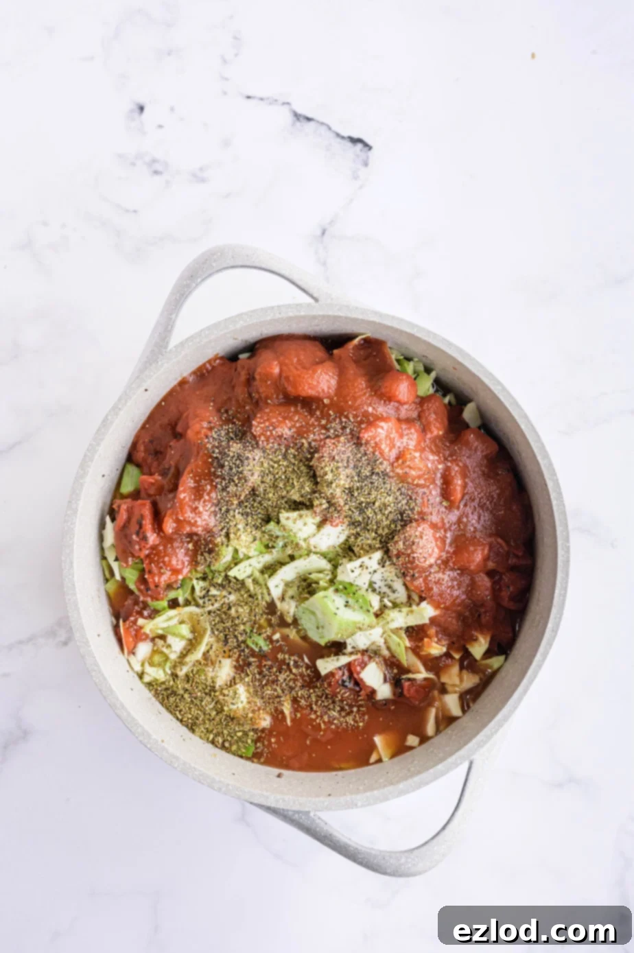 Raw ingredients for unstuffed cabbage roll soup are added to a large white pot on a stovetop, ready for cooking.