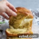 A hand tearing off a piece of garlic bread from a freshly baked vegan pull-apart loaf.