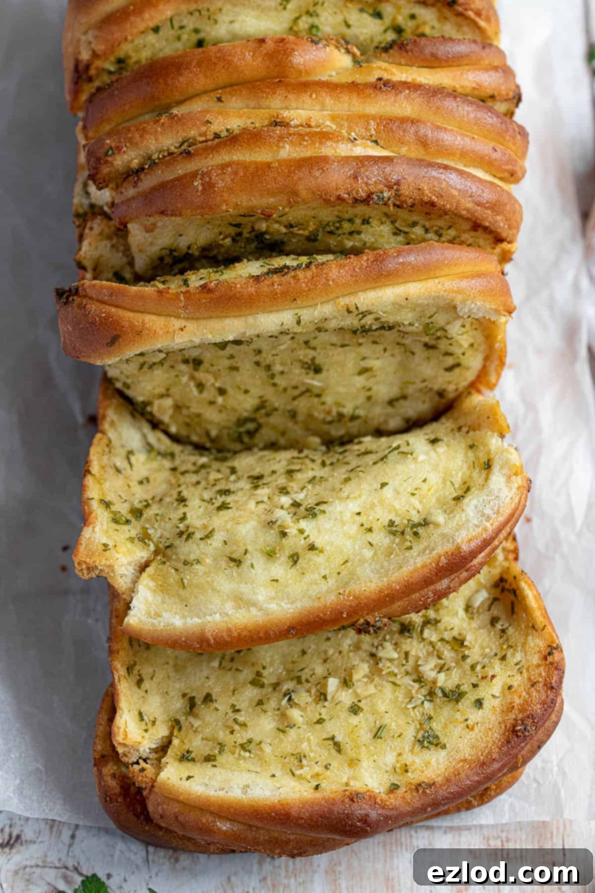 Close-up shot of individual sections of vegan garlic pull apart bread, showing the layers of bread and herb garlic butter, ready to be pulled apart.