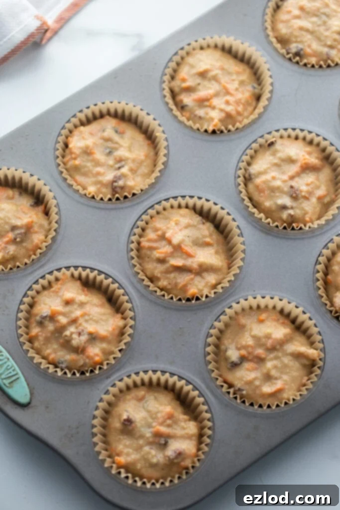 Muffin tin with carrot cake muffin batter, ready for the oven.