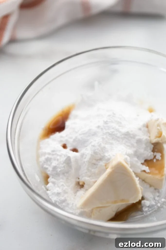 Ingredients for lightened up cream cheese frosting, in a glass mixing bowl