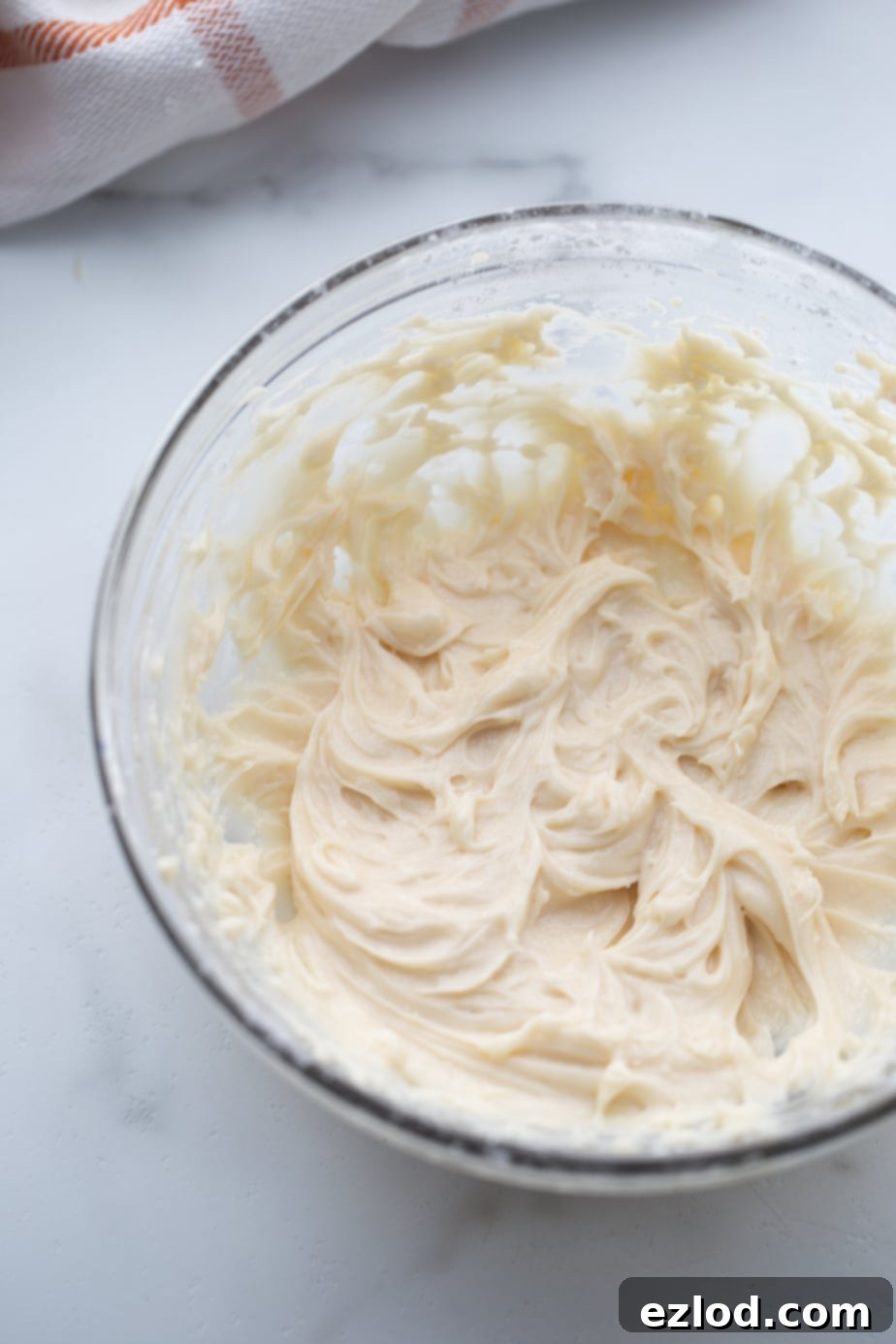 Lightened up cream cheese frosting whipped in a glass bowl