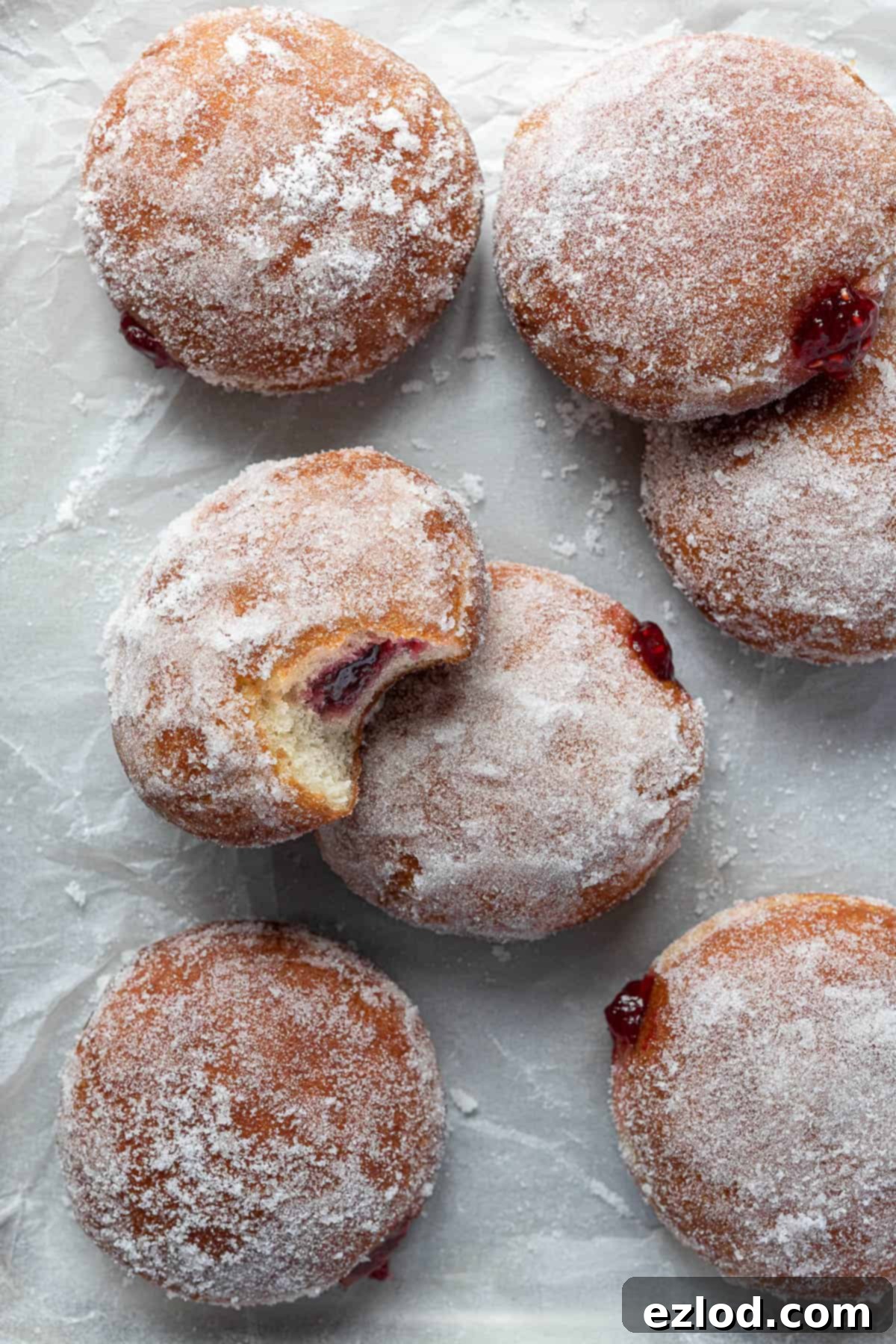 Vegan jam doughnuts on a sheet of baking parchment.