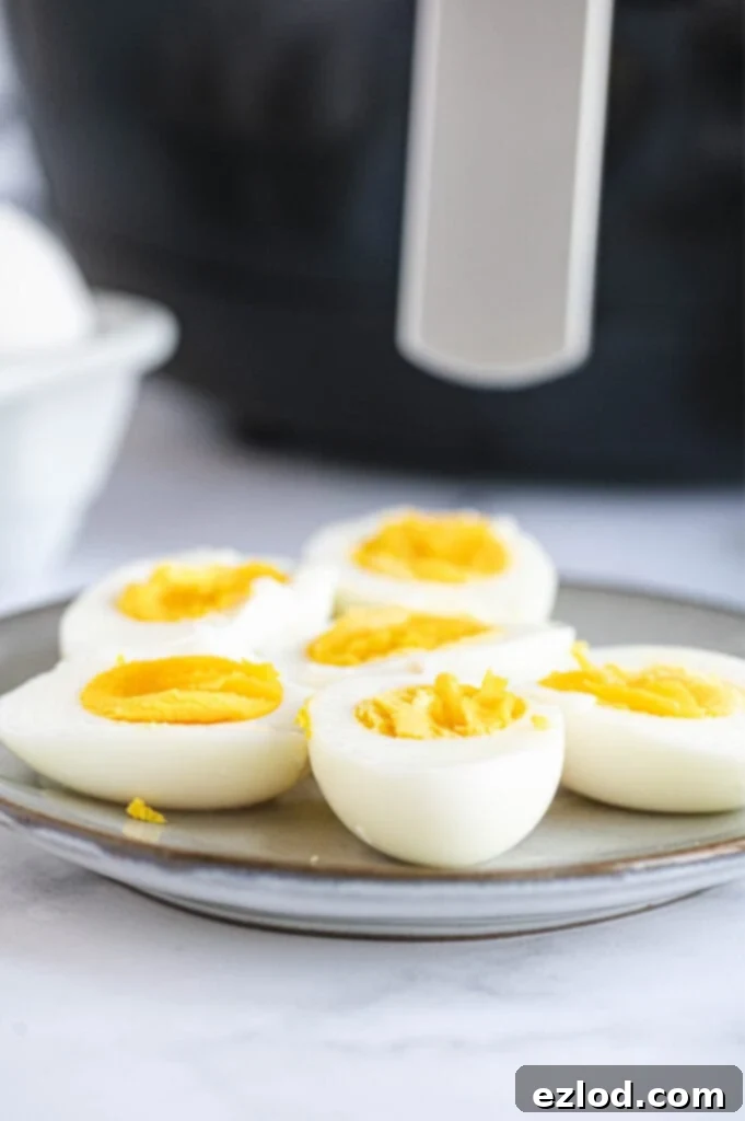 A plate of halved eggs is placed in front of the air fryer, showcasing the finished product.