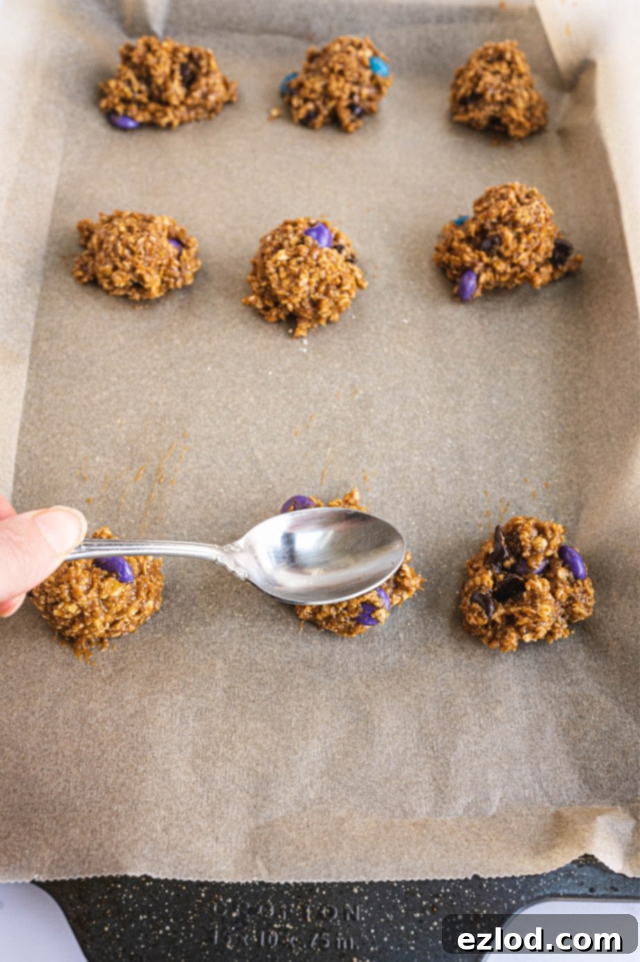 A small cookie scoop is pressing down on a mound of monster cookie dough, showing its perfect consistency for shaping.