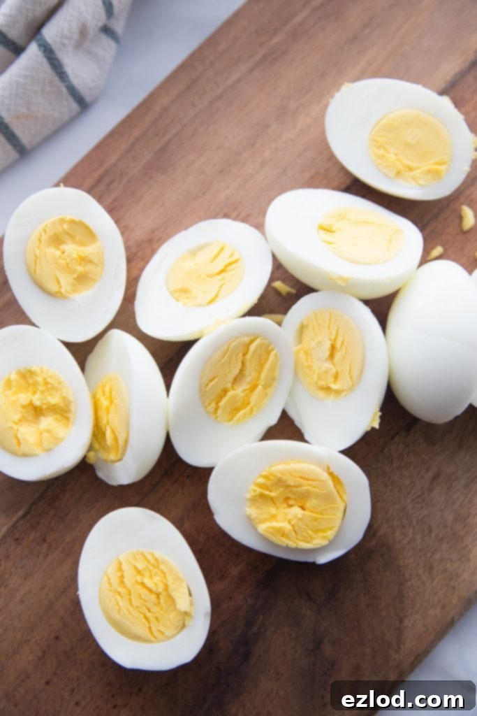Many perfectly peeled hard boiled eggs, cut in half, arranged beautifully on a rustic wooden cutting board