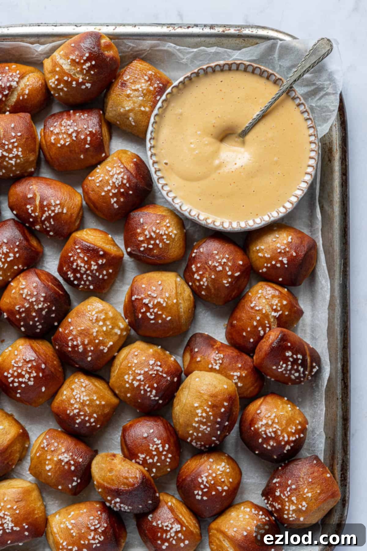 Pretzel bites on a metal tray with a bowl of sriracha cashew dipping sauce.