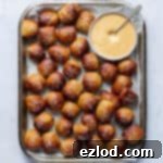 A tray of vegan pretzel bites with a bowl of dipping sauce on a marble background.