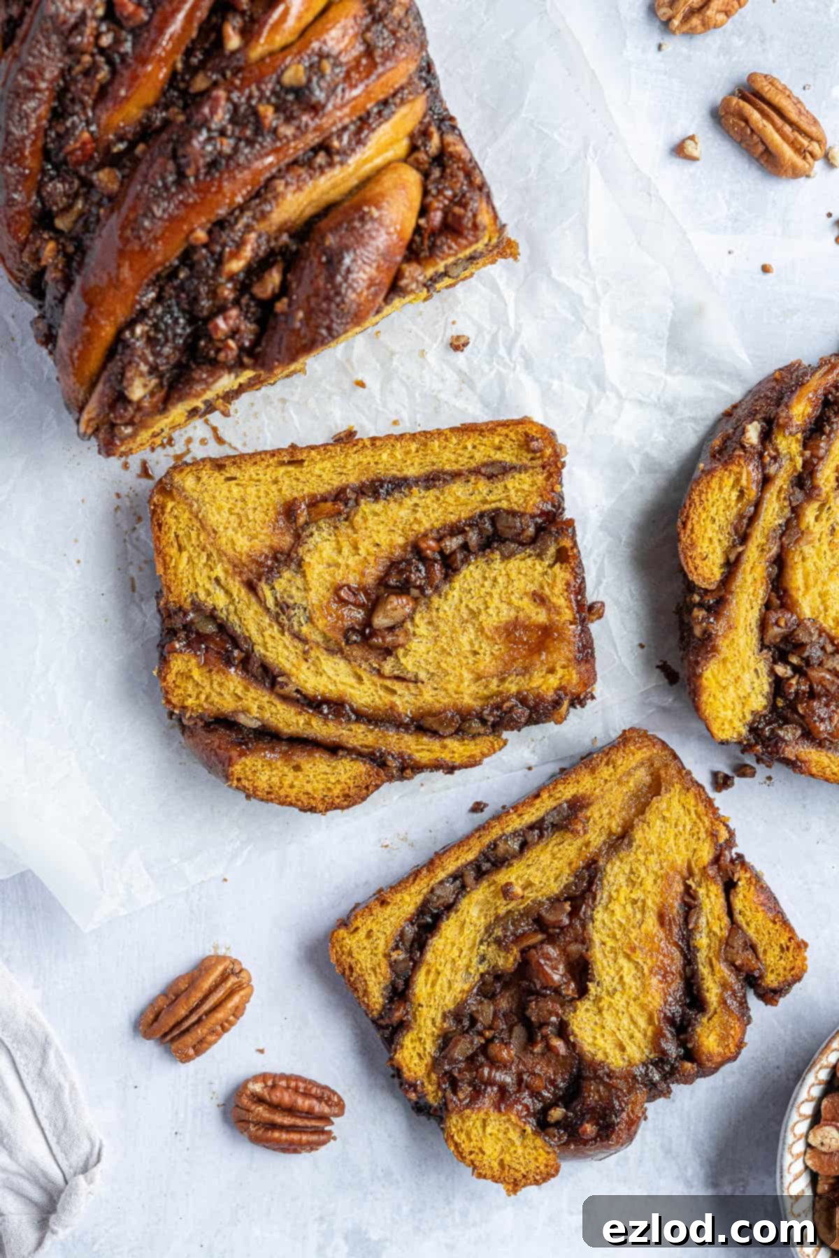 Two slices of vegan pumpkin pecan babka on white baking parchment.