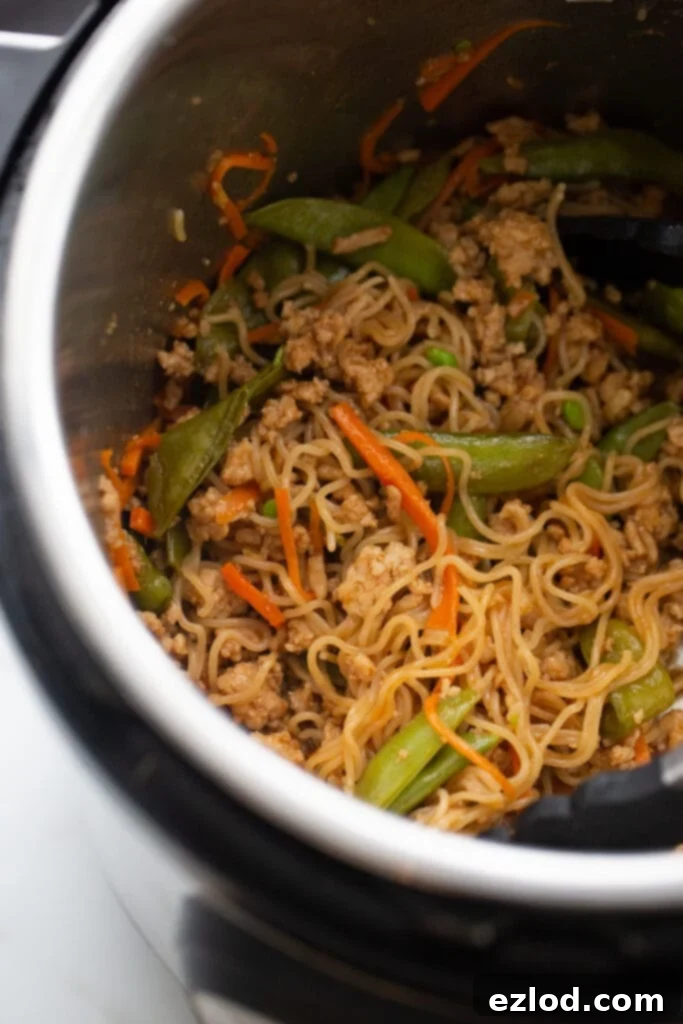 Overhead photo of Instant Pot with stir fry veggies, ramen, and ground chicken.