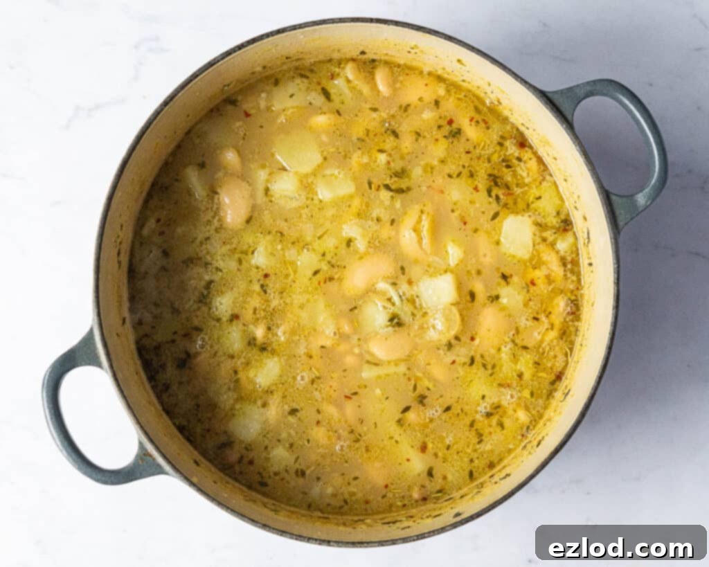 Step three: The cooked soup, featuring tender potatoes and softened cannellini and butter beans, ready for the next stage of blending.