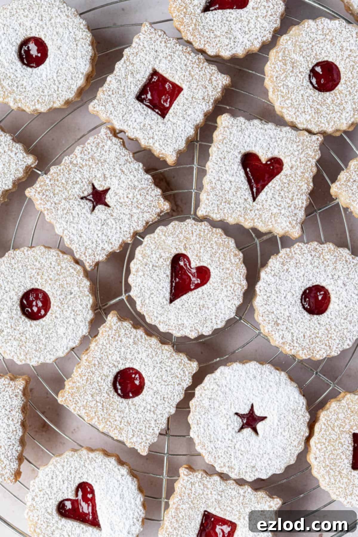 A stunning display of fully assembled vegan Linzer cookies, showcasing their perfect jam centers and powdered sugar dusting.