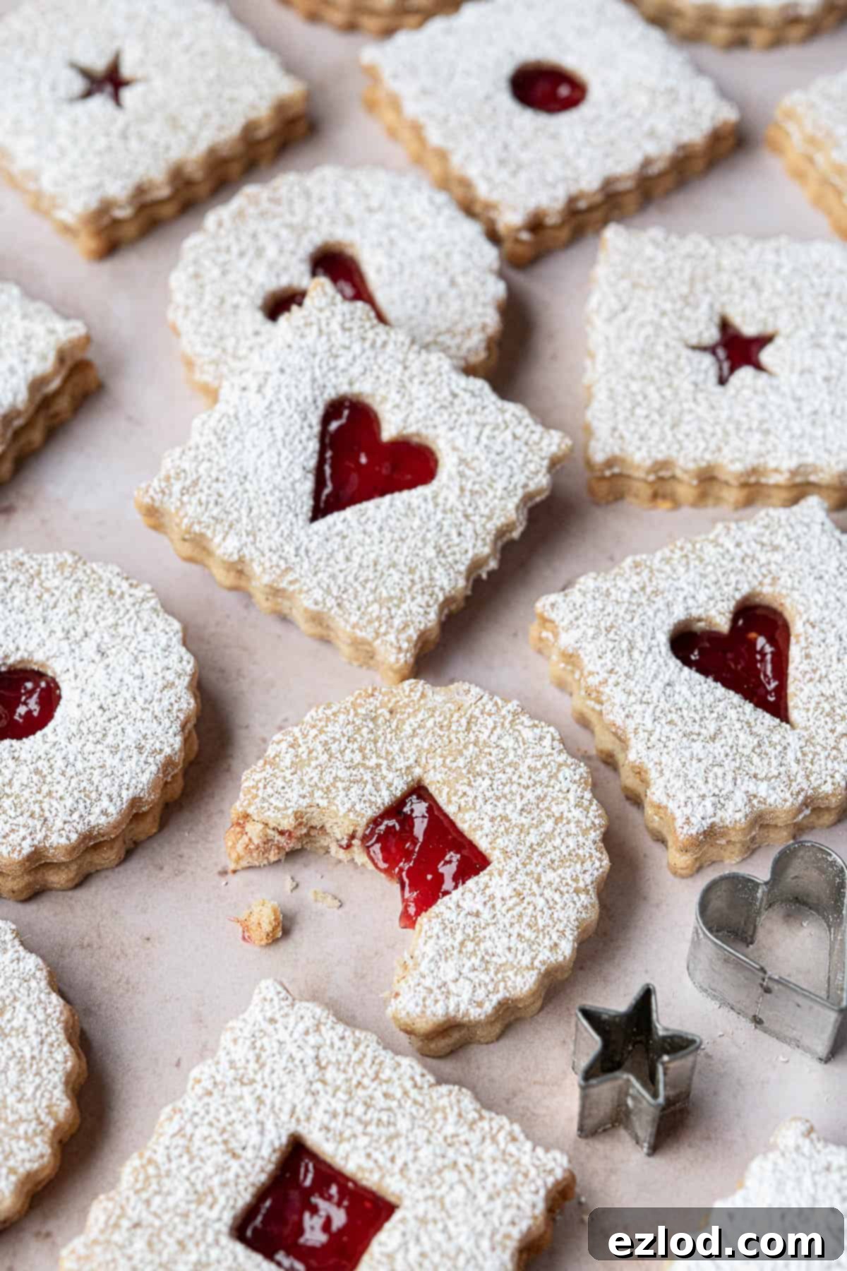 A detailed close-up of a vegan Linzer cookie with a perfect bite taken out, revealing the textured shortbread and glistening raspberry jam filling.