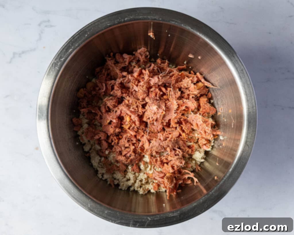 Step 4: Finely flaked young green jackfruit, after being thoroughly drained and squeezed to remove all excess moisture, sitting in a bowl. Its fibrous, shred-like texture is visible, demonstrating how it mimics the flakiness of fish in the vegan 'fish' cakes.