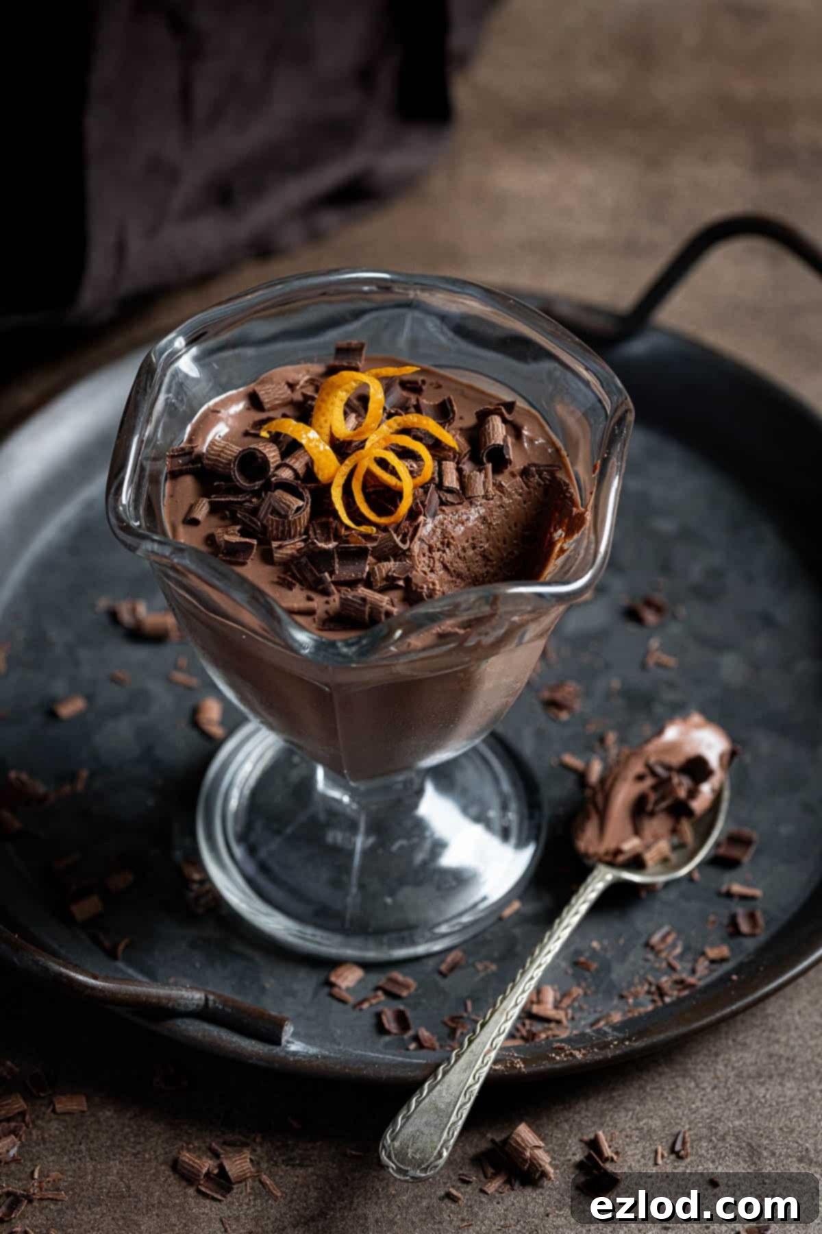 A single serving of a vegan chocolate orange pot on a metal tray with a spoonful removed, showing its rich, smooth texture.