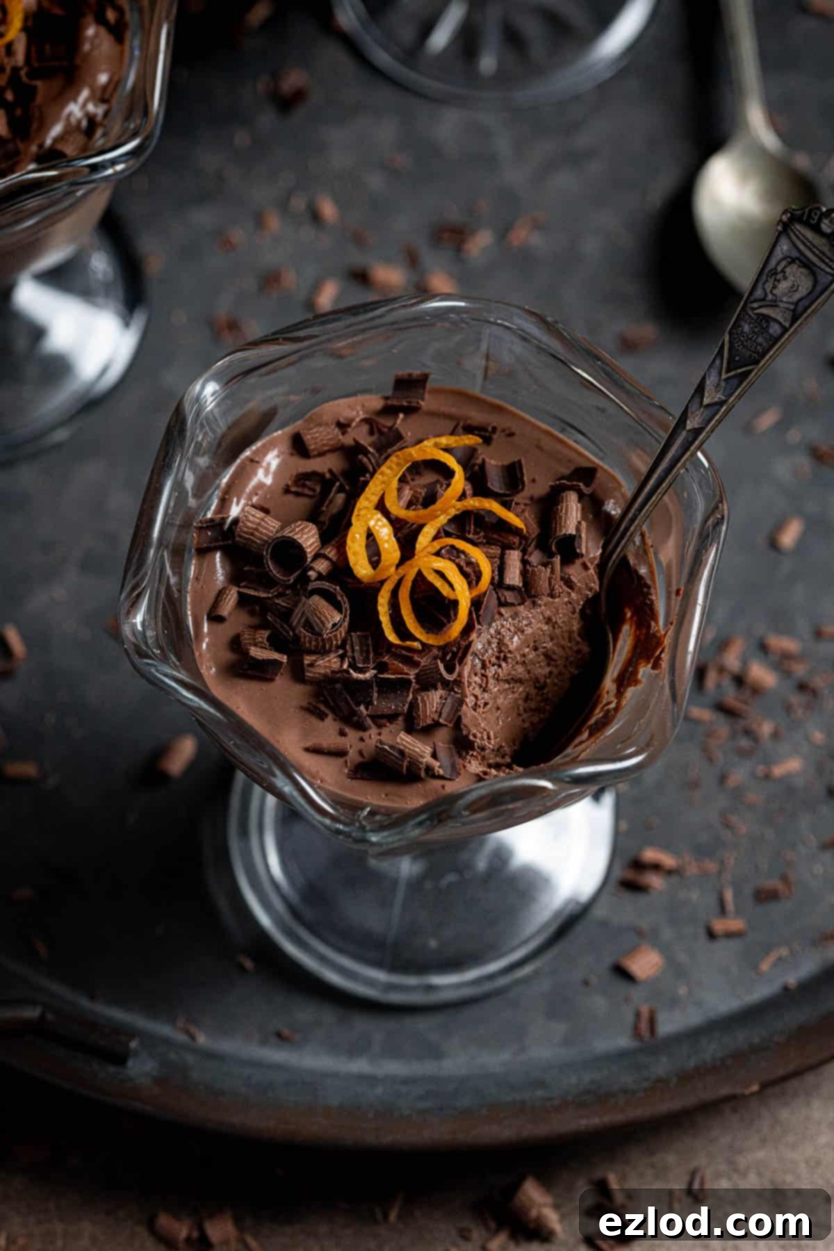A close-up shot of a single vegan chocolate orange pot with a spoonful removed, highlighting its luscious, set texture and rich color.