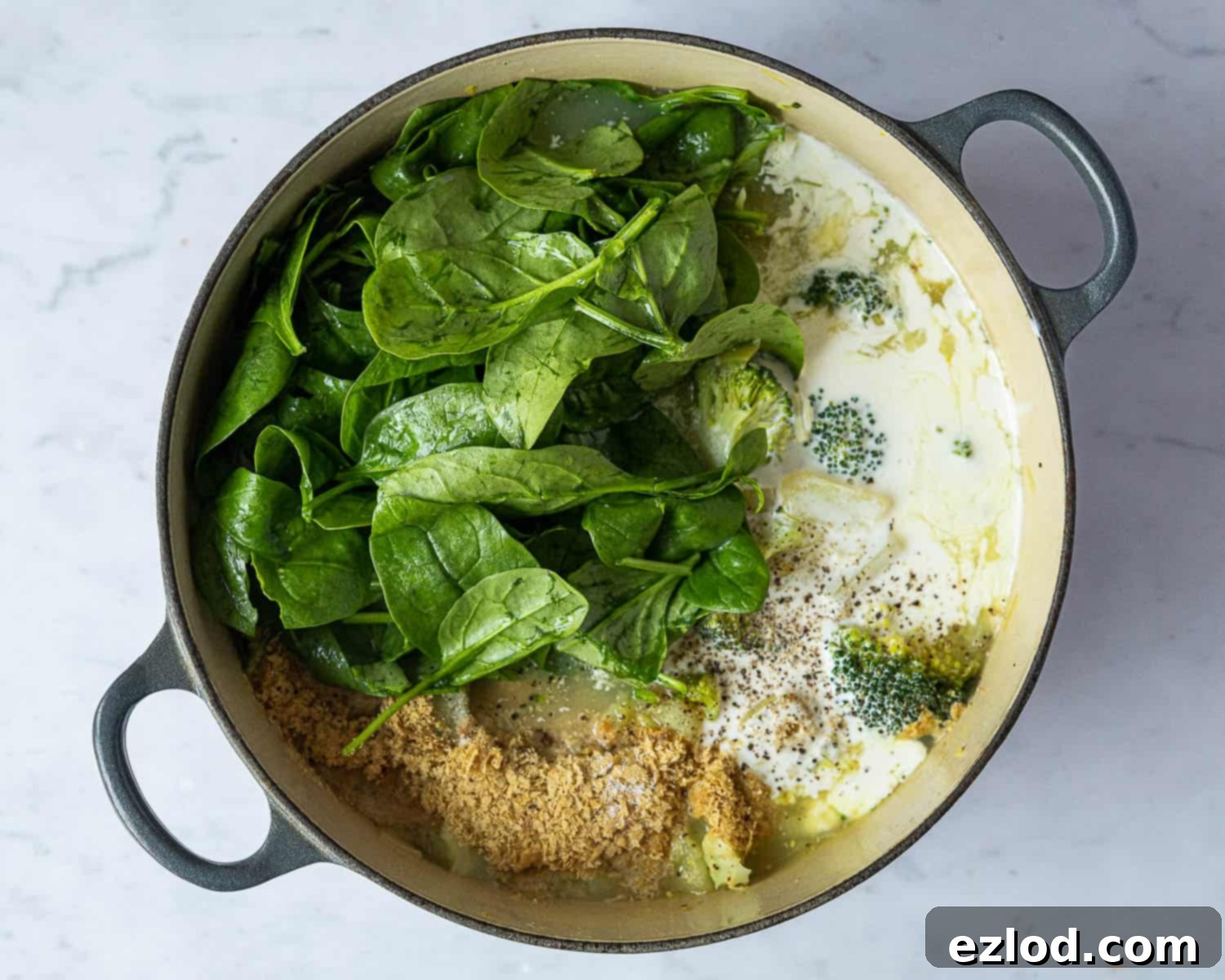 Creamy Vegan Broccoli Cheese Soup 7 Step 4 in making vegan broccoli soup: Fresh spinach, vegan cream, and nutritional yeast are added to the cooked vegetables in a blender, ready to be processed into a creamy soup.
