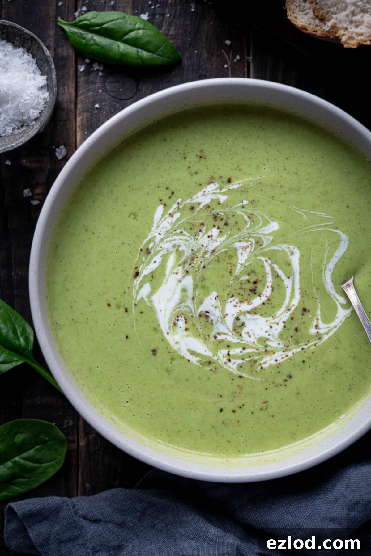 Creamy Vegan Broccoli Cheese Soup 8 A close-up view of a full bowl of creamy cheesy vegan broccoli soup, garnished with a sprig of fresh herbs, emphasizing its inviting and comforting texture.