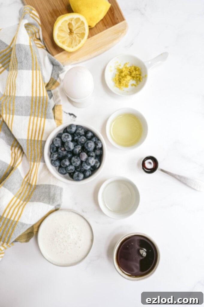 An overhead shot showcasing all the fresh, wholesome ingredients for the Healthy Lemon Blueberry Bread neatly arranged on a pristine white marble countertop. You can see bright yellow lemons, a bowl of plump blueberries, various flours, and other essential baking components, all ready to be transformed into a delicious and healthy loaf.