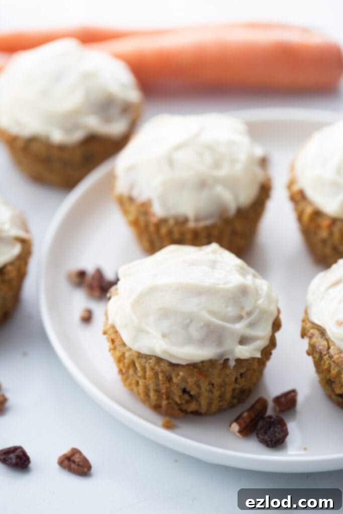 Healthy Carrot Cake Muffins, beautifully topped with a luscious cream cheese frosting, elegantly arranged on a round white plate, perfect for Easter or any brunch celebration.