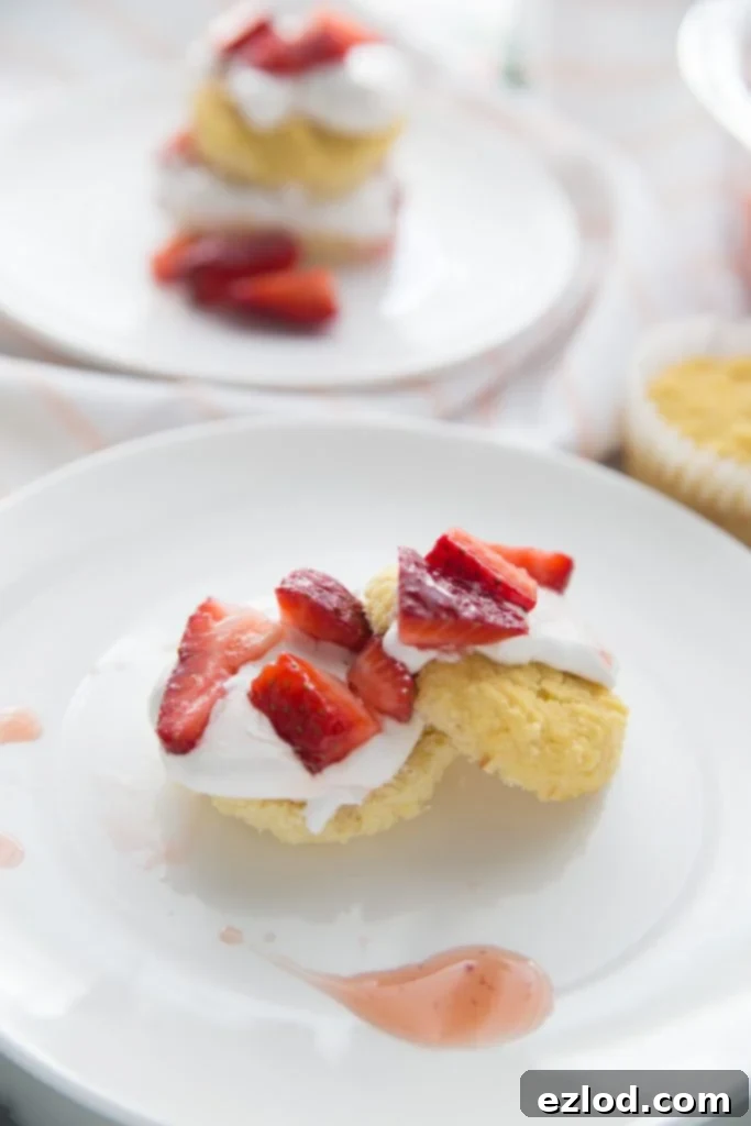 Individual healthy strawberry shortcakes, beautifully assembled with fresh berries and fluffy biscuits, presented on a white plate, perfect for a warm weather brunch dessert.