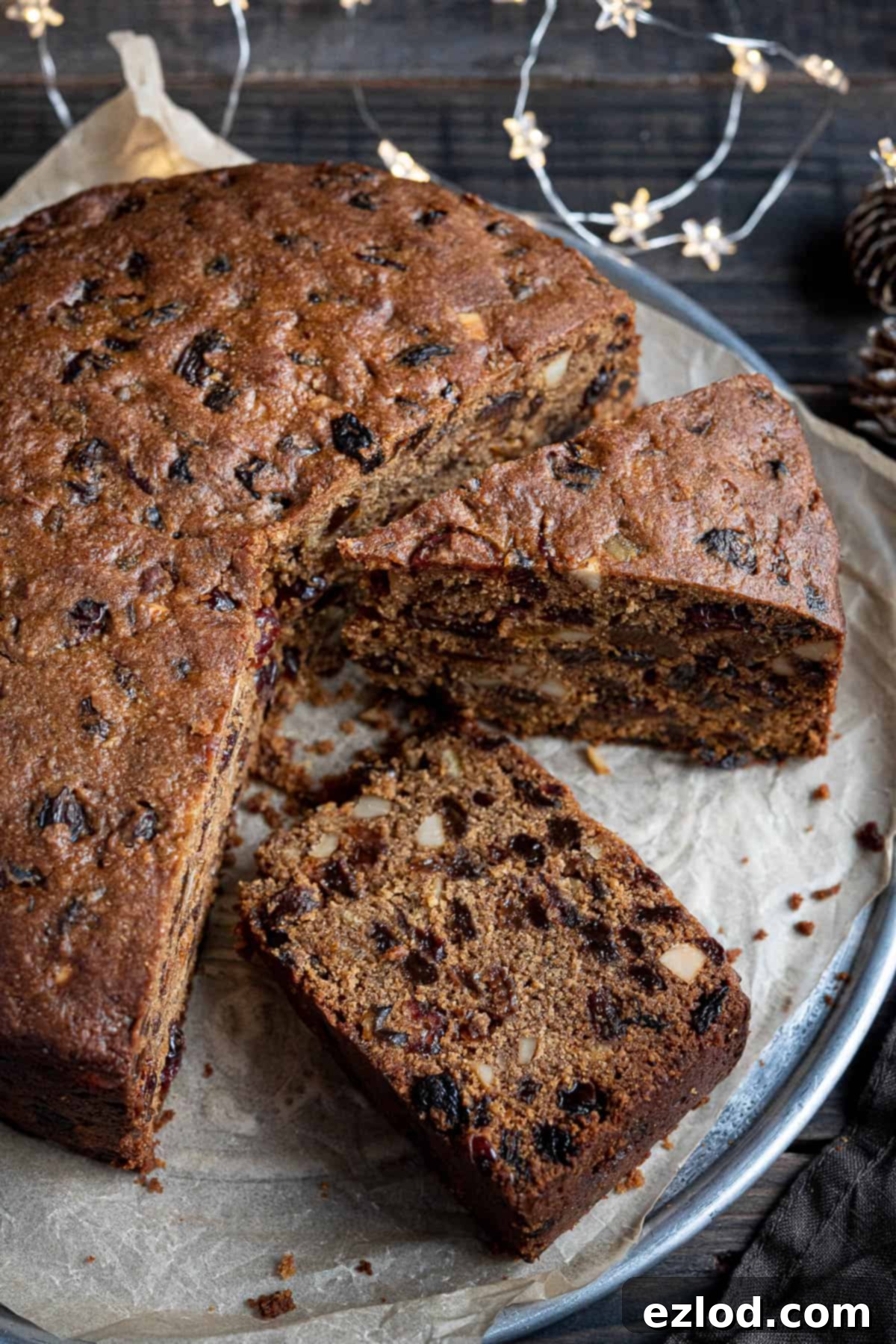 A close-up of a meticulously sliced gluten-free vegan Christmas cake, highlighting its rich fruit and nut content.