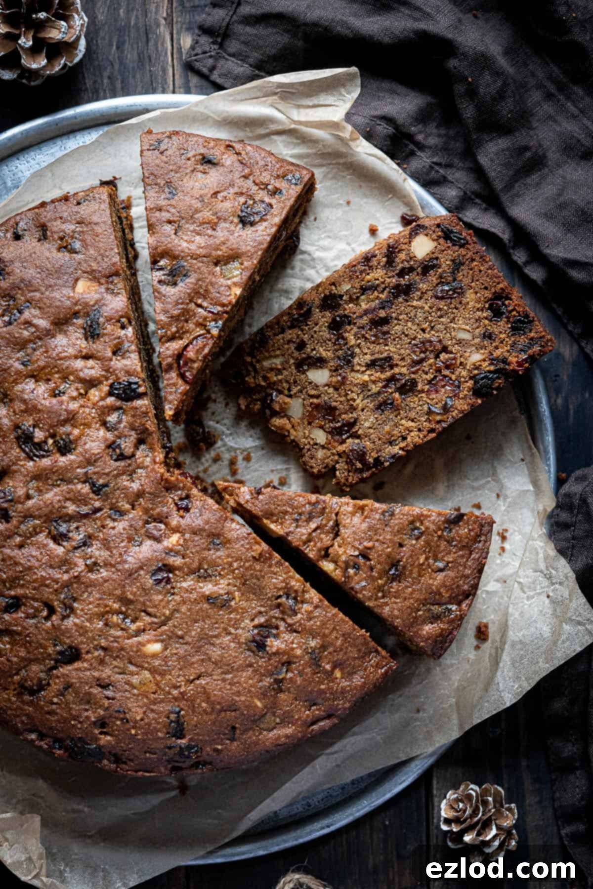 A large gluten-free vegan Christmas cake, perfectly baked and sliced, resting on a metal tray.