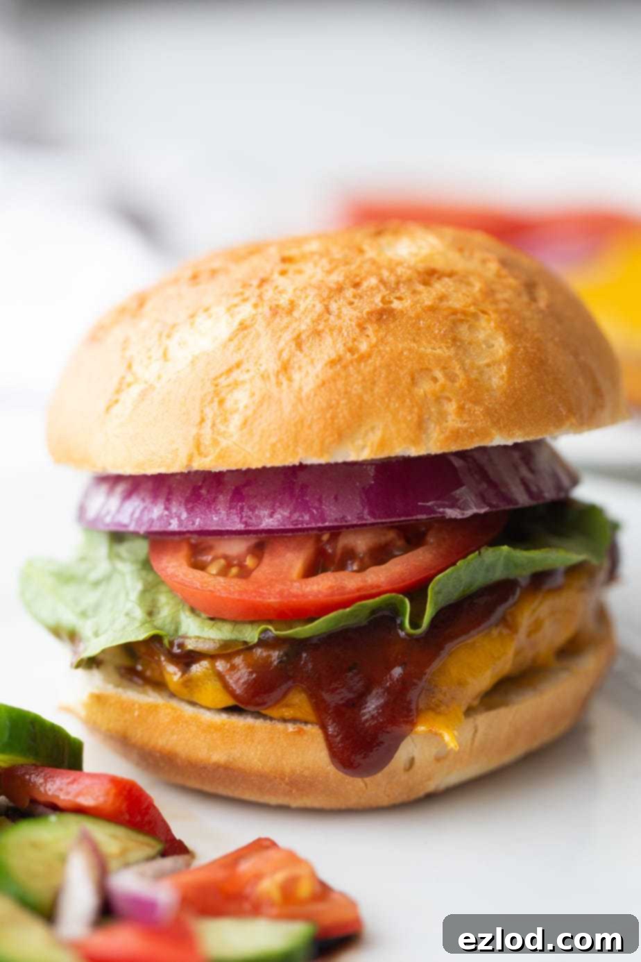 BBQ Chicken Burgers Air Fryer and Grill 2 A close up of a BBQ Chicken Burger with lettuce, onion, tomatoes and an extra drizzle of BBQ sauce