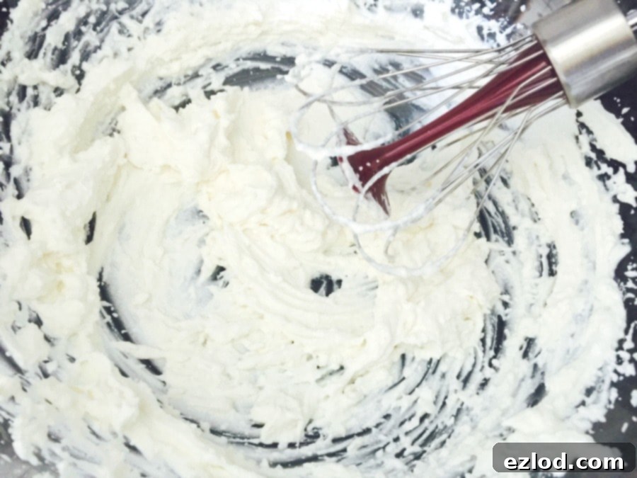 Close-up of fluffy whipped ricotta with a splash of almond milk, showcasing its smooth and creamy texture after mixing.