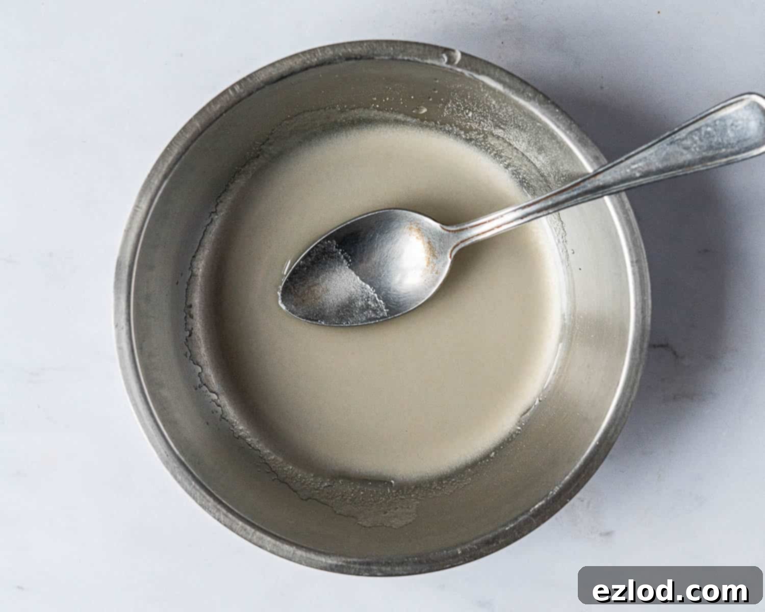 Agar agar powder mixed with cold water to form a slurry, an essential step before adding it to the raspberry puree for setting the mousse.