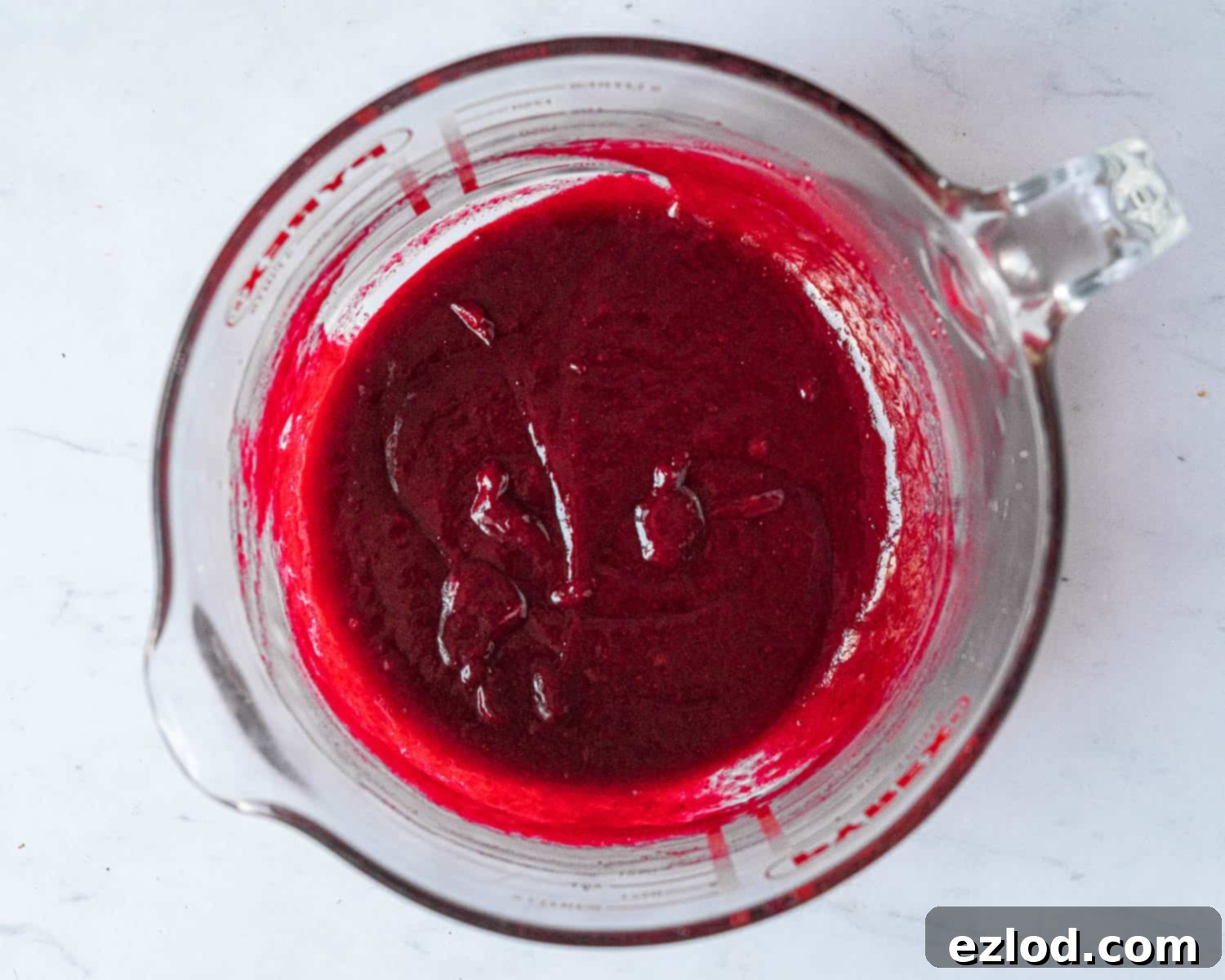 The vibrant raspberry white chocolate mixture, smooth and melted, after combining the hot raspberry puree with chopped vegan white chocolate.