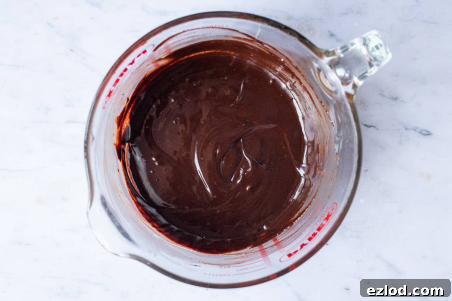 The melted dark chocolate ganache, a rich and glossy mixture of cream and chocolate, cooling in a bowl for the mousse layer.
