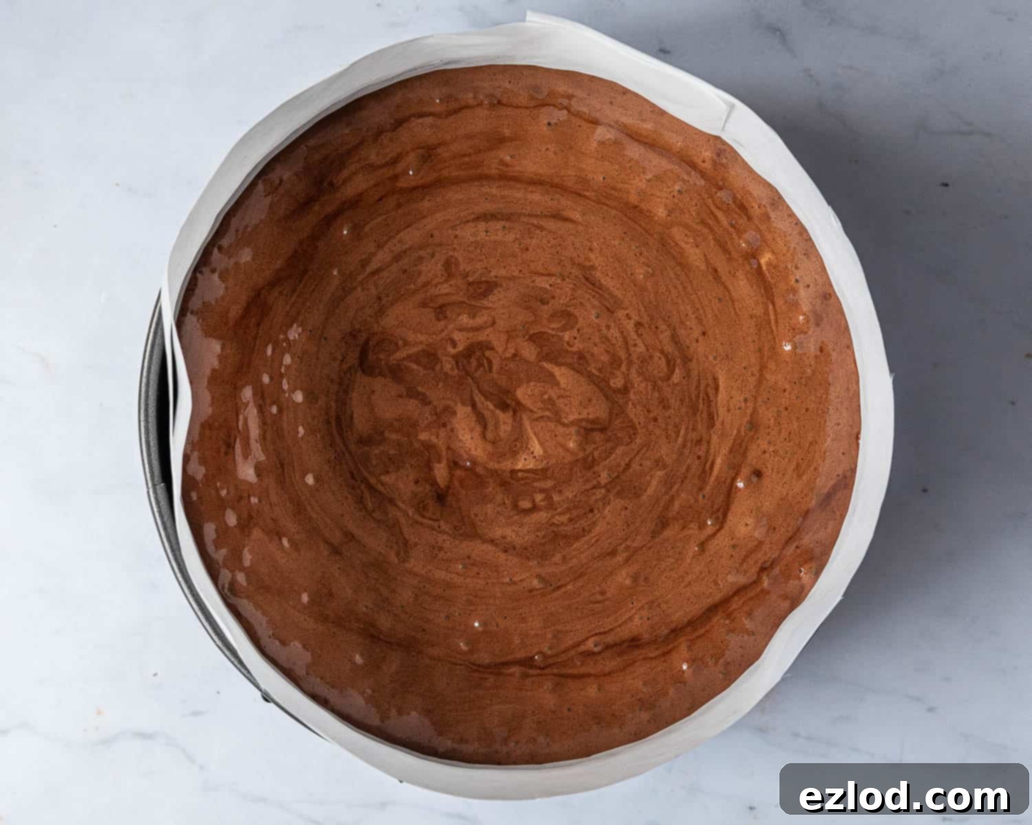 The dark chocolate mousse layer perfectly spread over the chocolate cake within the lined springform tin, chilling in the fridge.
