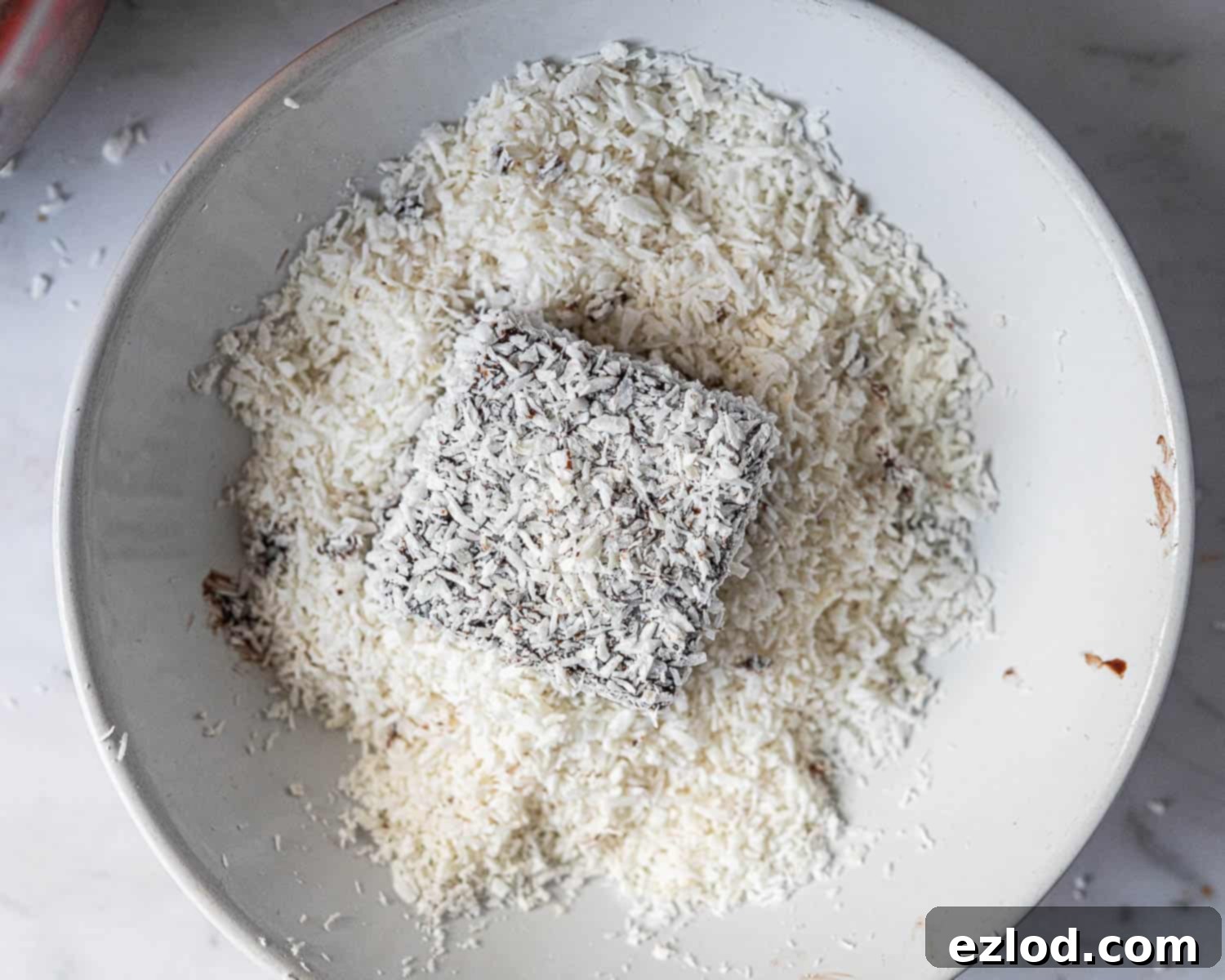 Step 7, coating the Lamington in coconut.