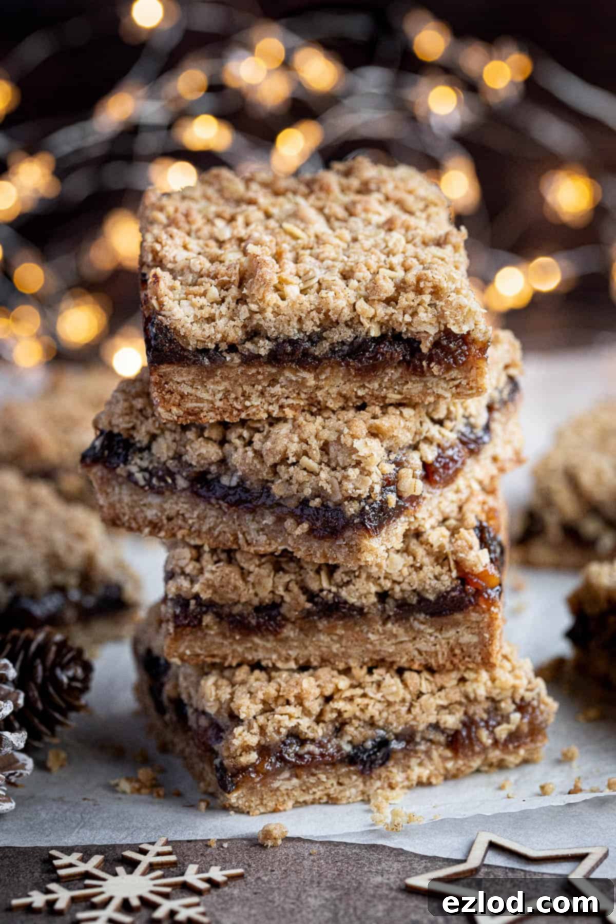 Vegan Mincemeat Crumb Bars 2 A stack of golden brown vegan mincemeat crumble bars, featuring a thick, oat-filled base and crumble topping with a sweet, fruity mincemeat filling visible.