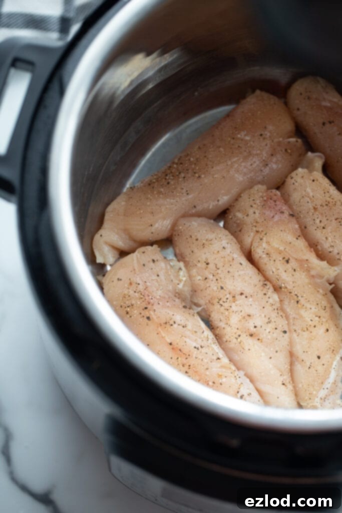 Ultimate Healthy Grape Chicken Salad Recipe 4 Raw chicken breasts seasoned with salt, pepper, and garlic powder, placed inside an Instant Pot, ready for cooking.