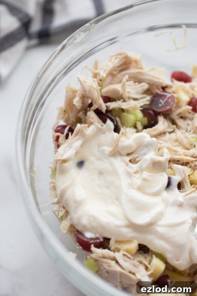 Ultimate Healthy Grape Chicken Salad Recipe 7 The chicken and fruit mixture, now topped with a creamy white dressing made from Greek yogurt and mayonnaise, awaiting the final mix.
