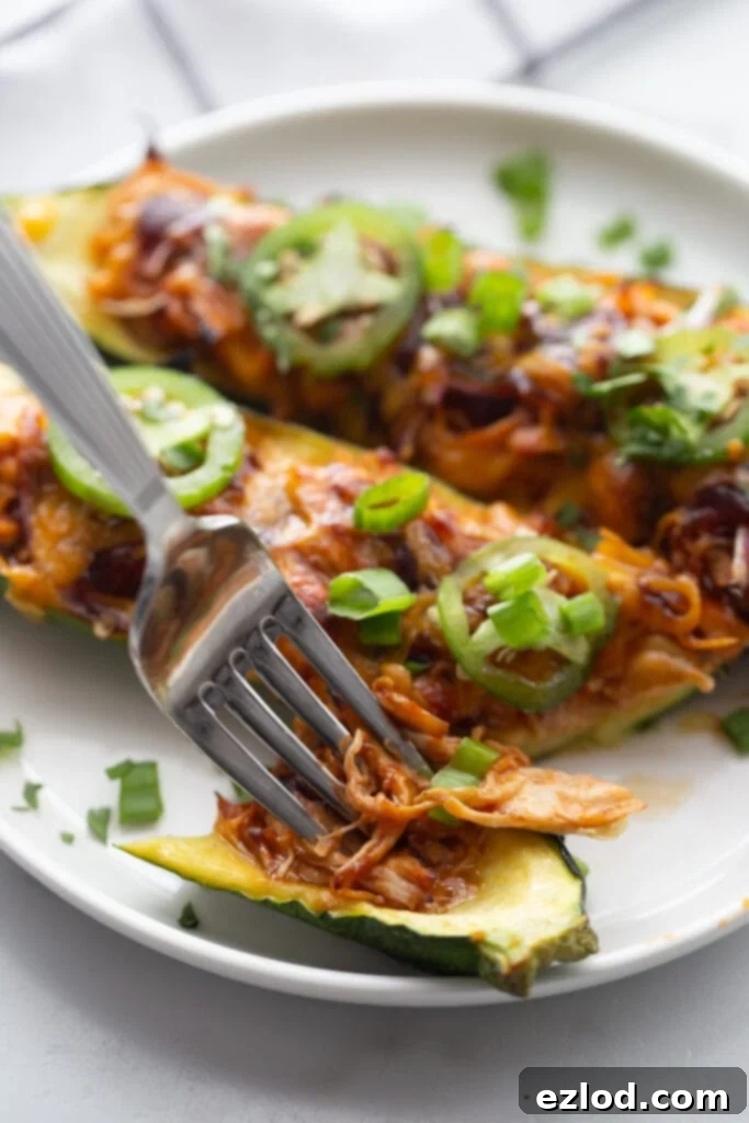 Stuffed zucchini boats on a plate with a bite on a fork, ready to be eaten