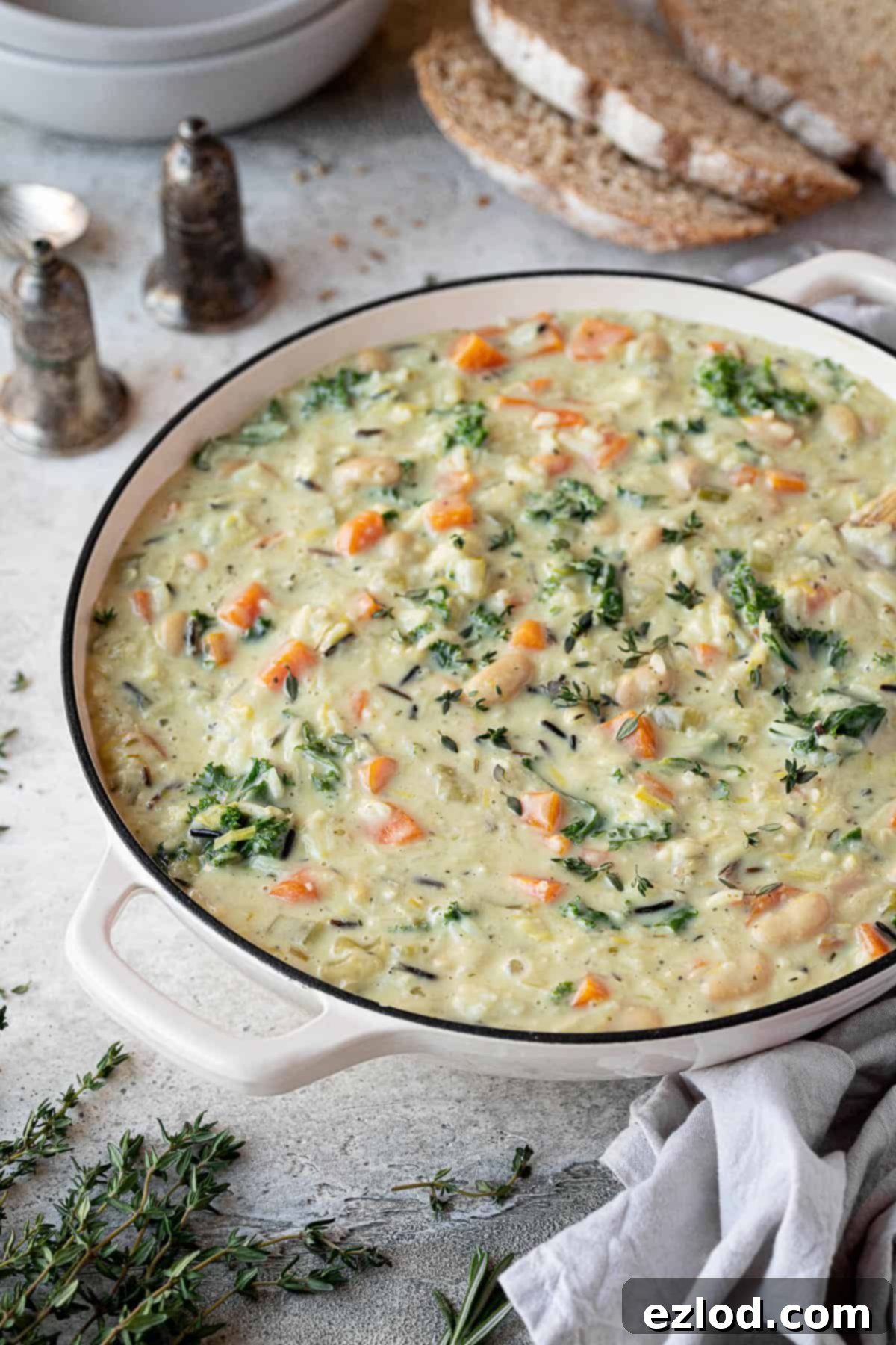 Close up of a pan of creamy vegetable rice soup, showcasing its rich texture and colorful vegetables.
