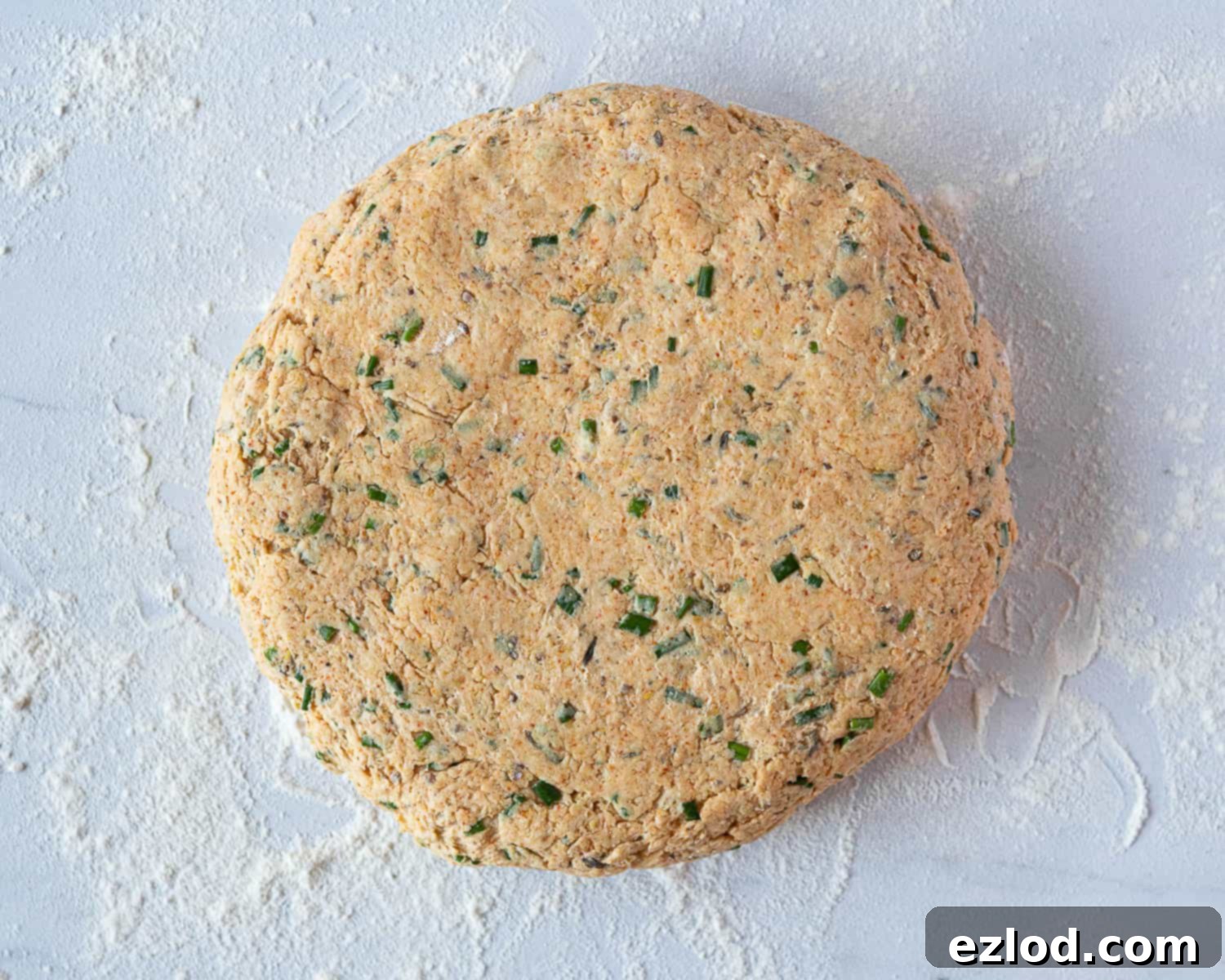 Step 5: The savoury vegan scone dough patted out evenly on a floured surface to the specified thickness.