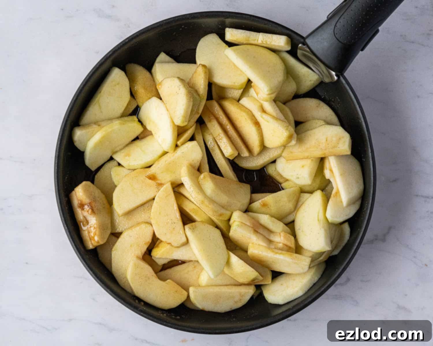 Step 1 in making vegan Eve's pudding: Peeled, cored, and sliced apples are placed in a pan with brown sugar, vanilla extract, lemon juice, and water, ready for stewing.
