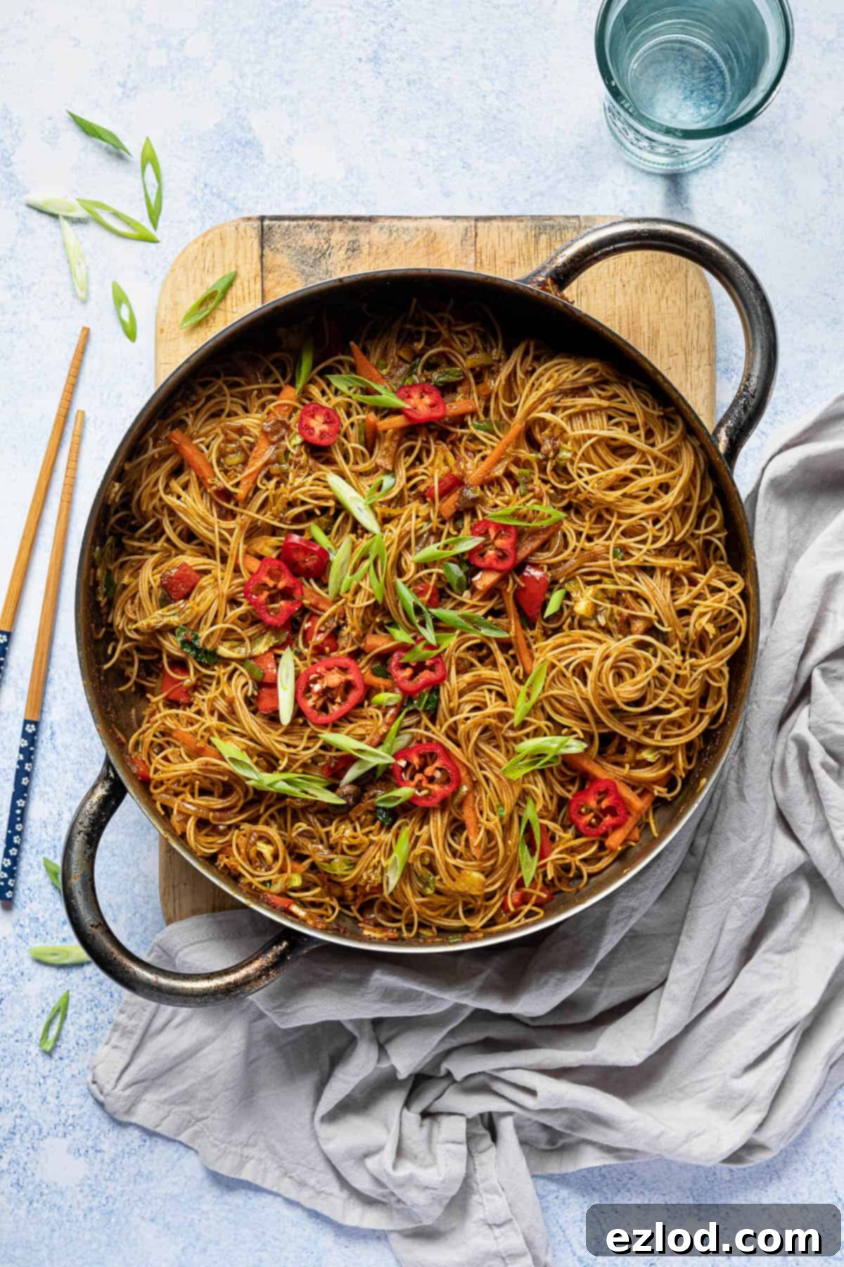 Curry noodles in a pan on a wooden board.