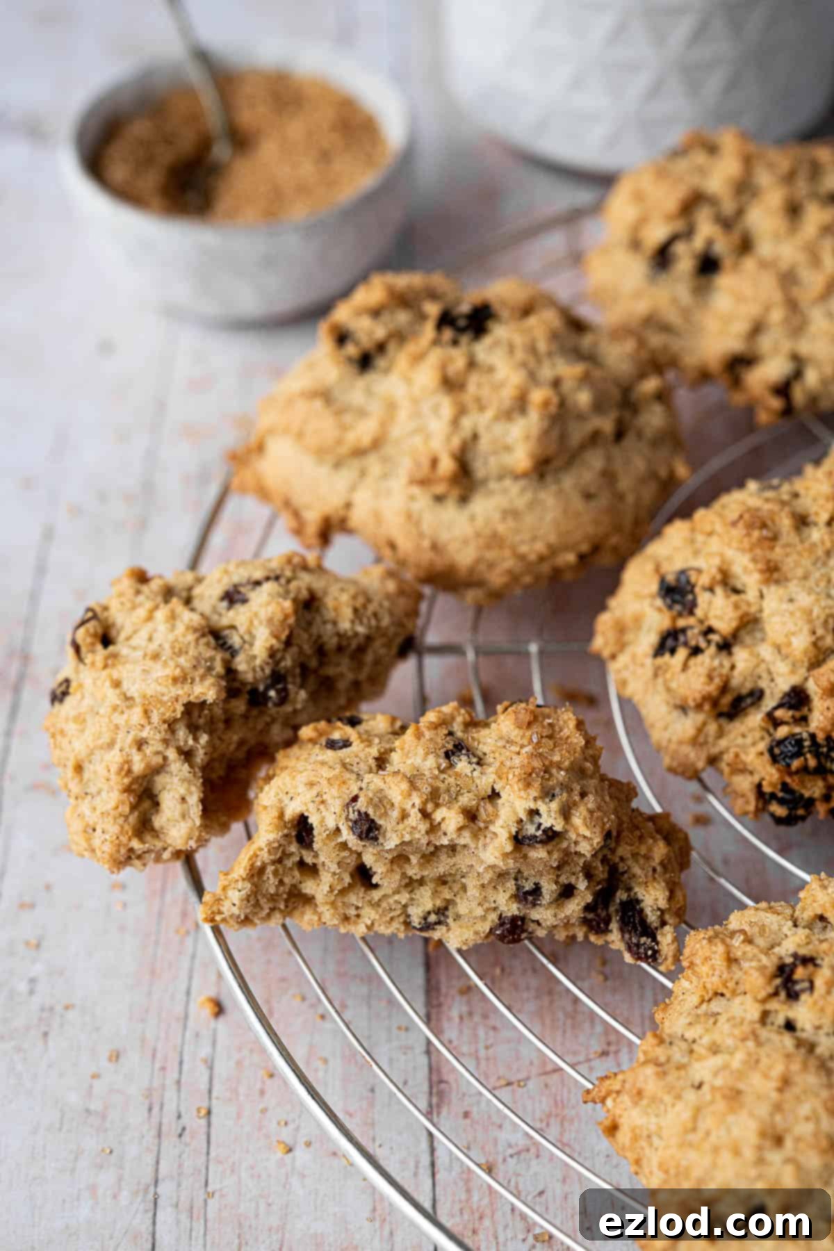 Close up view of a vegan rock cake, perfectly split in half to reveal its moist, crumbly interior filled with dried fruit.