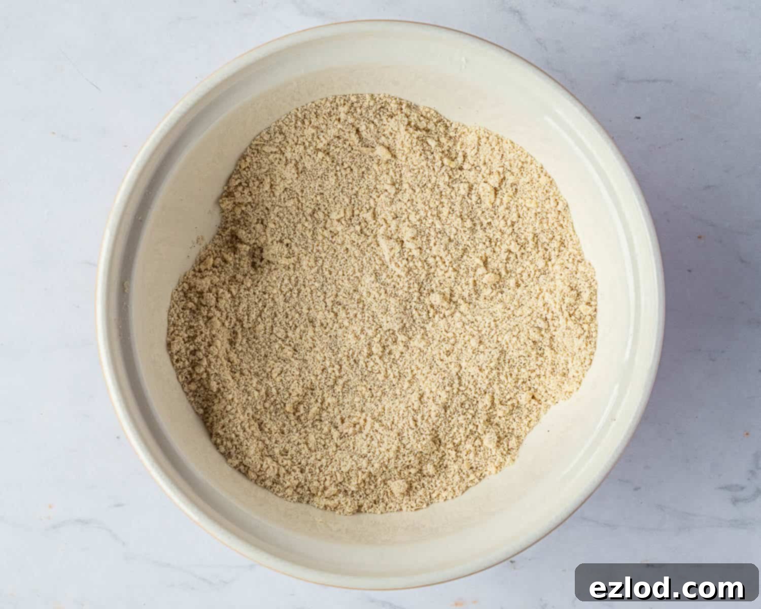 Step 2 in making vegan rock cakes: Diced cold vegan butter is rubbed into the dry flour mixture until it resembles fine breadcrumbs.