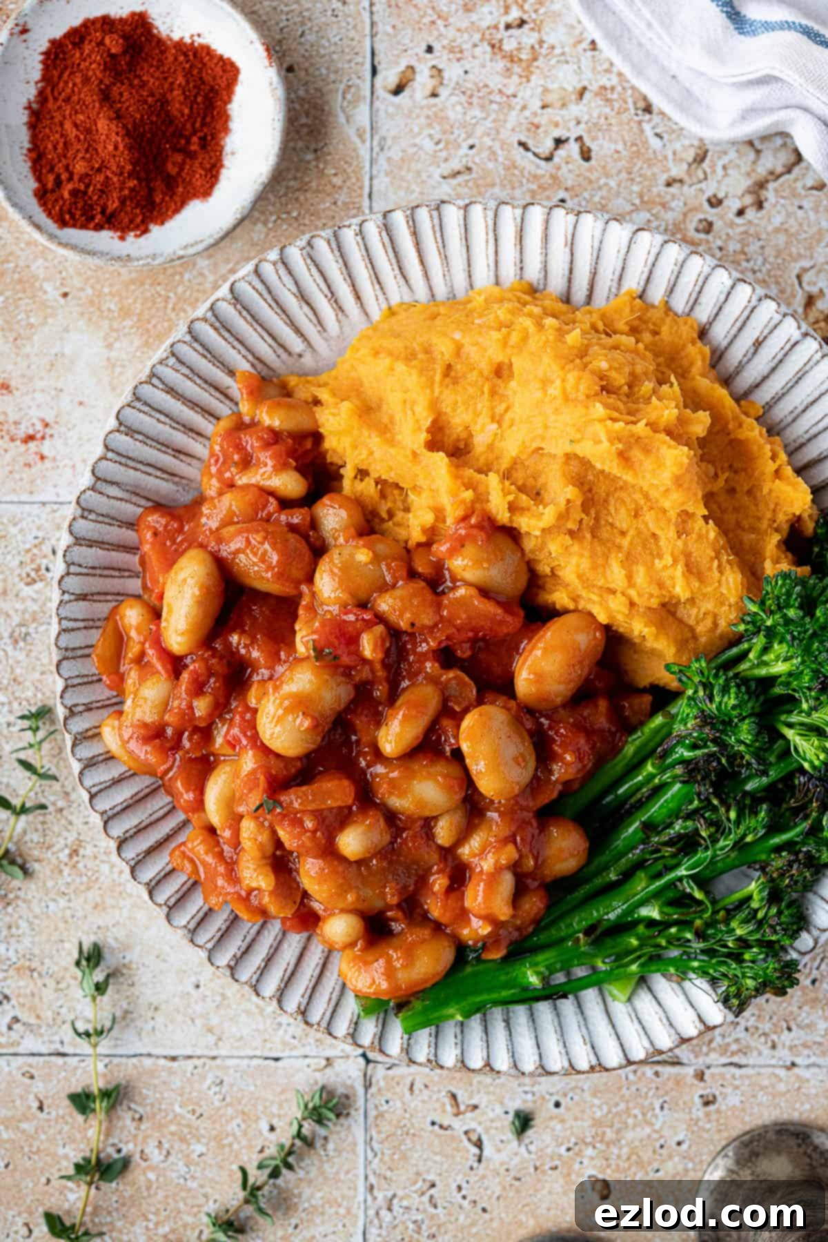 Hearty Smoky Tomato Beans 3 Close-up of a plate featuring smoky tomato beans, perfectly paired with fluffy sweet potato mash and bright green steamed broccoli, highlighting a complete vegan meal.