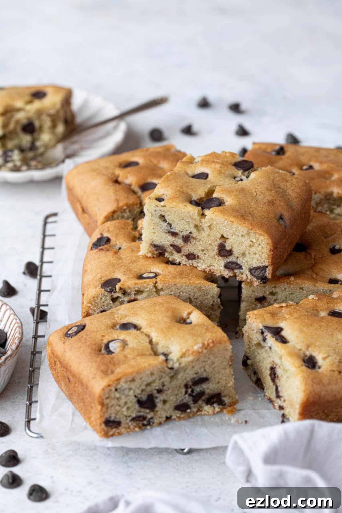 A stack of squares of vegan chocolate chip vanilla cake, showcasing its soft texture and abundant chocolate chips.