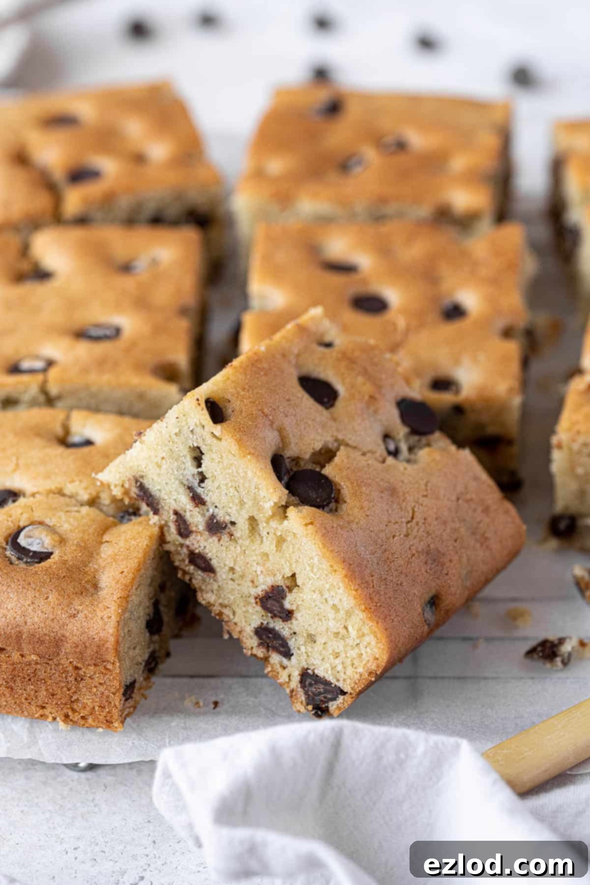 A close-up view of a single square of moist vegan chocolate chip vanilla cake, showcasing its tender crumb and melted chocolate chips.