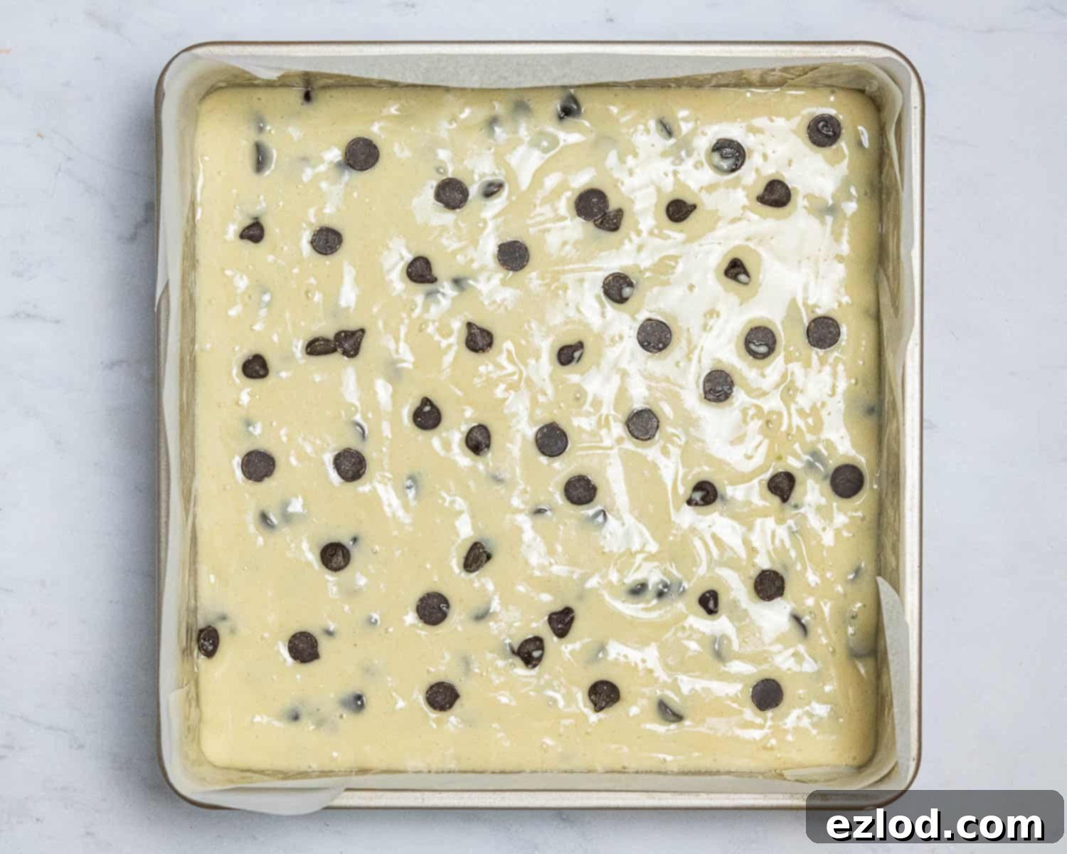 Step 5: The smooth vegan chocolate chip vanilla cake batter poured into a prepared square baking tin, ready for the oven.